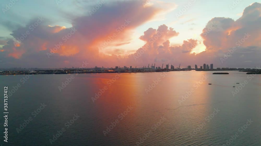 Aerial view over the sea towards the buildings, in the Miami skyline, colorful dusk clouds and sky, in Florida, USA - dolly, drone shot Aerial view over the sea towards the buildings, in the Miami skyline, colorful dusk clouds and sky, in Florida, USA - dolly, drone shot