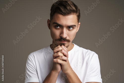 Image of tense unshaven guy posing and holding hands together