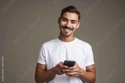 Image of joyful unshaven guy smiling and using cellphone © Drobot Dean