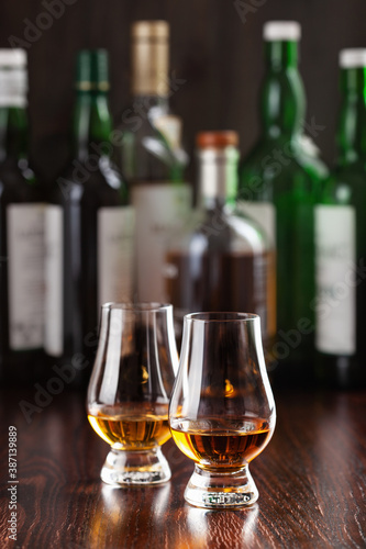 Bottles and glass of whisky spirit brandy on dark brown background