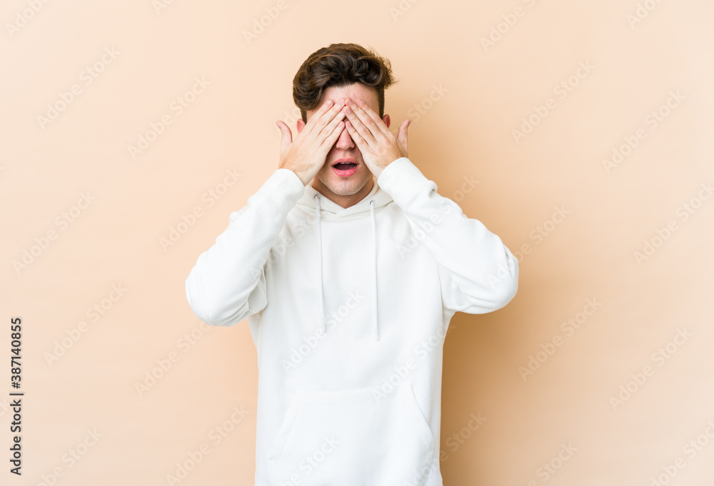 Young caucasian man isolated on beige background afraid covering eyes with hands. Young caucasian man isolated on beige background afraid covering eyes with hands.