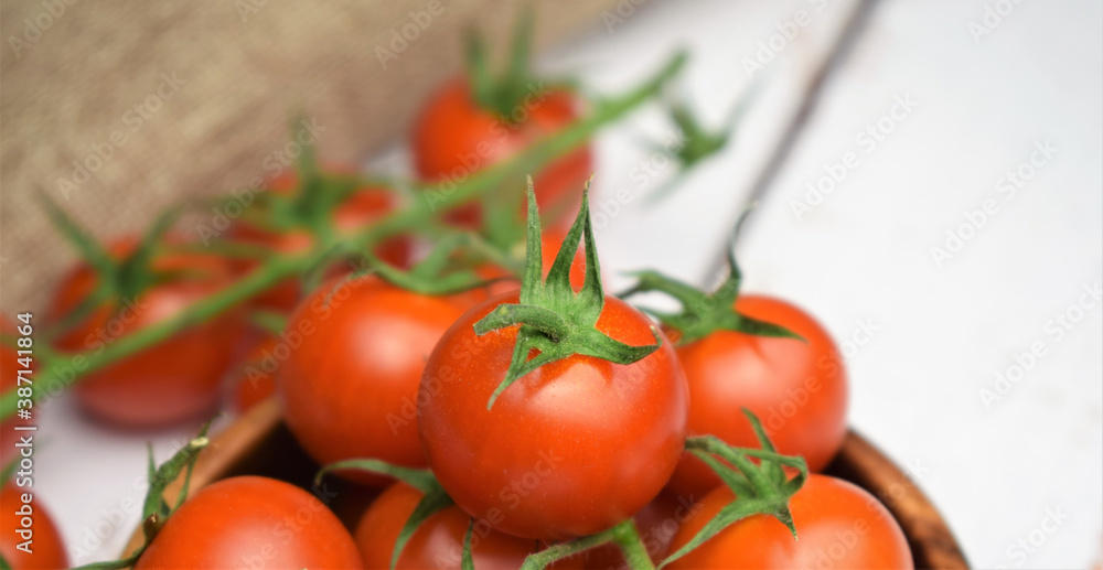 Natural presentation. Close up. Cherrys tomatoes on the branch on white wooden boards.