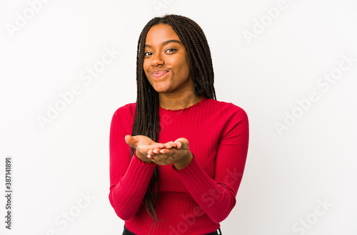 Young african american woman isolated holding something with palms  offering to camera.