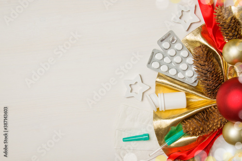 Tablets  an eyedropper  a jar for medicines and Christmas decorations lie on a white wooden table. Medical Christmas greeting card mockup with place for text. View from above. Copyspace
