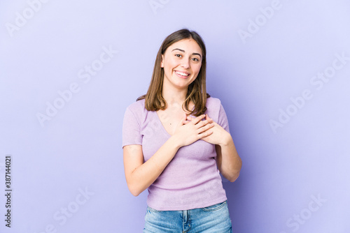 Young caucasian woman laughing keeping hands on heart, concept of happiness.