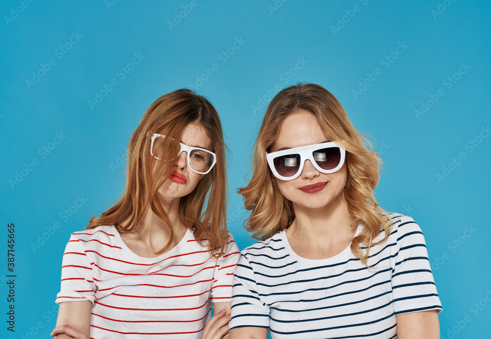 Obraz premium two cheerful girlfriends in striped t-shirts sunglasses hug friendship