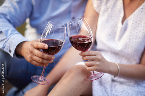 Male and female hands holding glasses of red wine outdoors. Red wine in a glass. Celebration concept