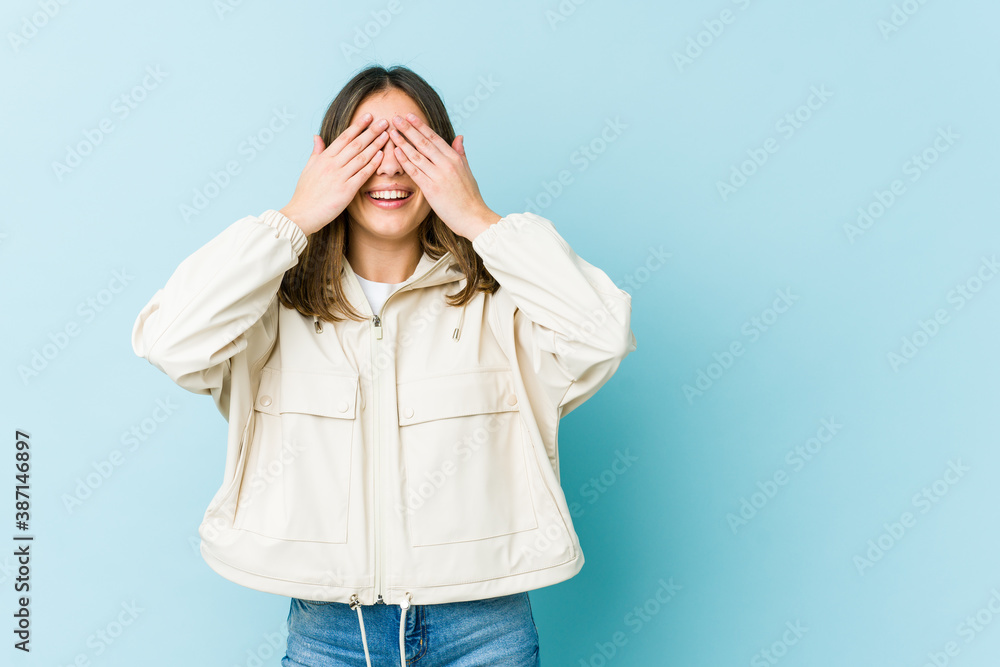 Young caucasian woman covers eyes with hands, smiles broadly waiting for a surprise. Young caucasian woman covers eyes with hands, smiles broadly waiting for a surprise.