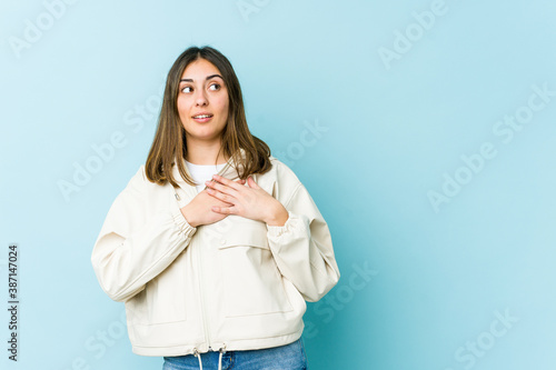 Young caucasian woman has friendly expression, pressing palm to chest. Love concept.
