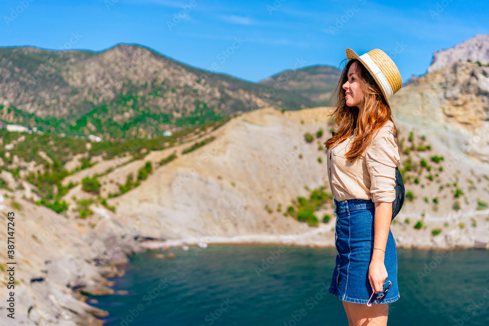 Beautiful young woman in a hat on vacation at Cape Kapchik with a view of the coast and the sea