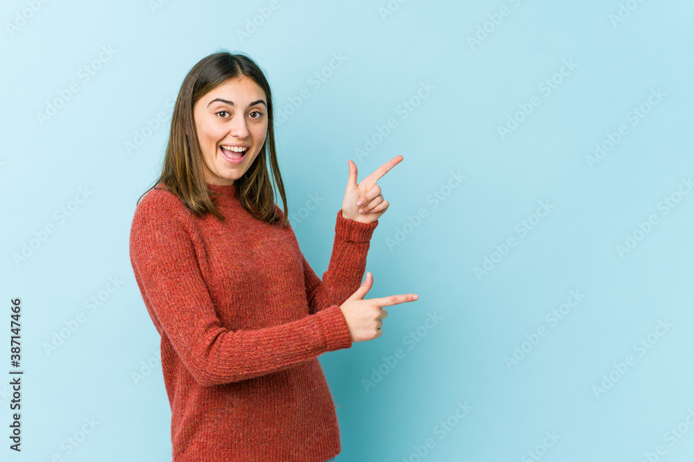 Young caucasian woman excited pointing with forefingers away. Young caucasian woman excited pointing with forefingers away.