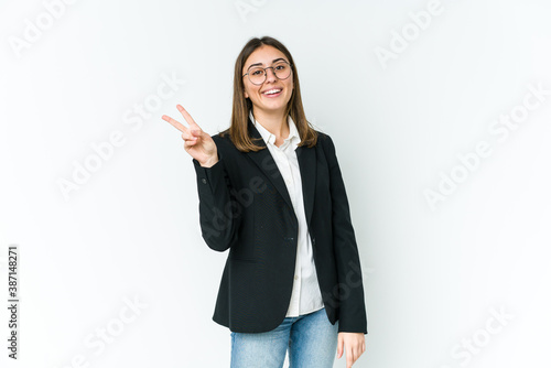 Young caucasian business woman joyful and carefree showing a peace symbol with fingers.