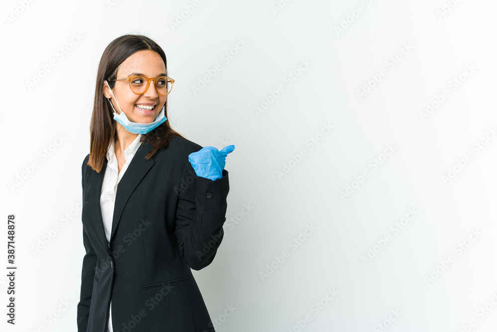 Young business latin woman wearing a mask to protect from covid isolated on white background points with thumb finger away, laughing and carefree. Young business latin woman wearing a mask to protect from covid isolated on white background points with thumb finger away, laughing and carefree.