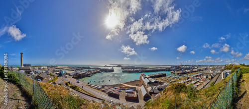 Panoramic image of St Helier Harbour with the town centre of St Helier, sea and blue sky with some clouds.