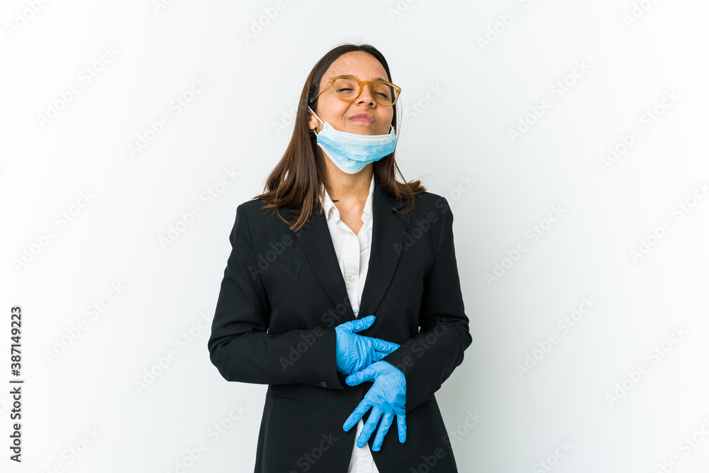 Young business latin woman wearing a mask to protect from covid isolated on white background touches tummy, smiles gently, eating and satisfaction concept. Young business latin woman wearing a mask to protect from covid isolated on white background touches tummy, smiles gently, eating and satisfaction concept.