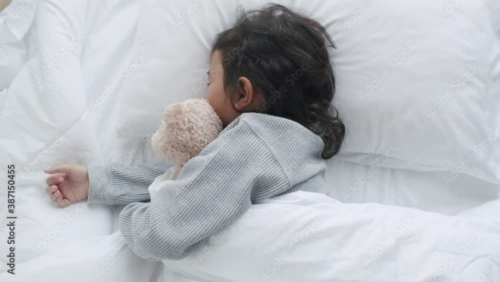 Asian little girl sleeping and hugging teddy bear in the bedroom Asian little girl sleeping and hugging teddy bear in the bedroom