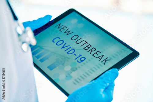 doctor and text covid-19 new outbreak in a tablet