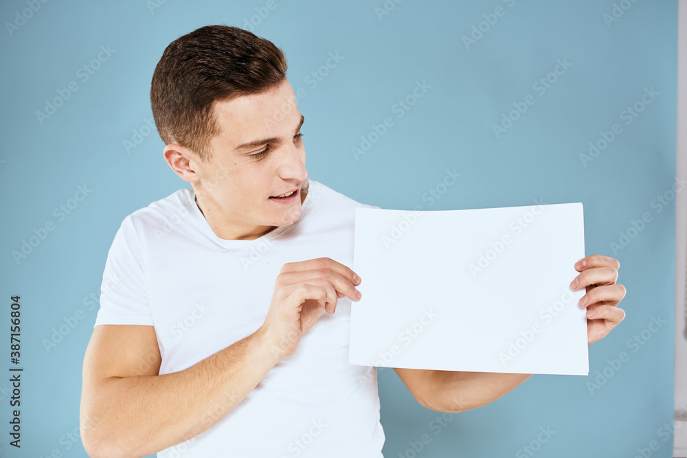 man holding a sheet of paper in his hands white t-shirt cropped view blue background man holding a sheet of paper in his hands white t-shirt cropped view blue background