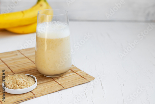Healthy banana smoothie on wooden board with maca and protein on white background Copyspace