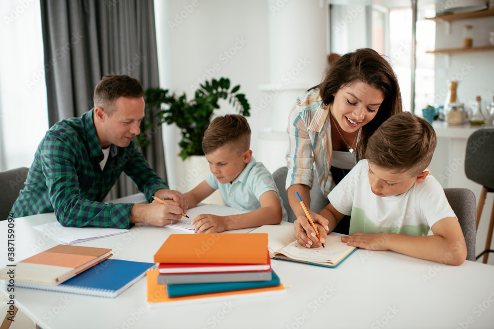 Parents helping the kids with their homework. Litlle boys learning at home Parents helping the kids with their homework. Litlle boys learning at home