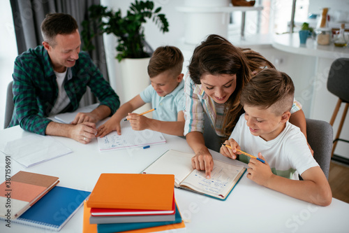 Parents helping the kids with their homework. Litlle boys learning at home