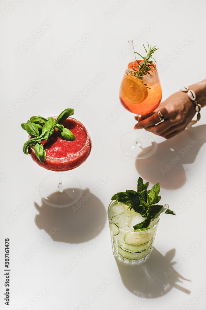 Popular bar summer ice alcoholic cocktails. Gin-tonic, Aperol Spritz and  strawberry basil Margarita in glasses and womans hand with glass over plain  white background with shadows Stock-Foto | Adobe Stock