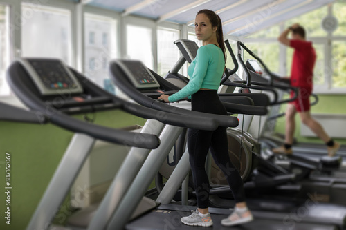 A young athletic woman walks or runs on a treadmill in a fitness room.Workout and Strength training theme. Cardio training. Healthy and Exercise activity concept.