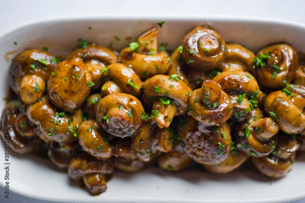 Fototapeta premium Mushrooms roasted in garlic, onions, olive oil and fresh herbs and spices. Classic American steakhouse or French bistro appetizer or side dish.