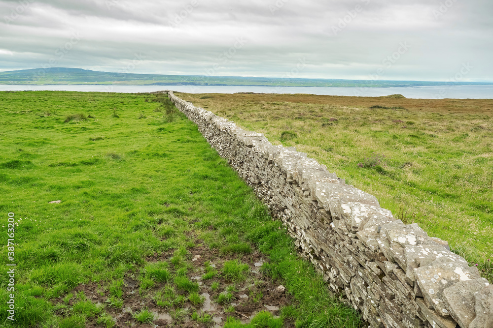 Dry stone fence in a field. West coast of Ireland. Nobody. Cloudy sky. Rural area