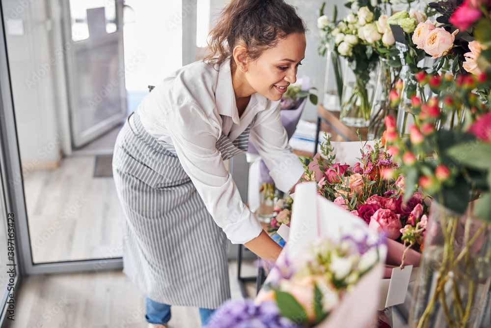 Charming female florist sorting out bouquets in a flower studio