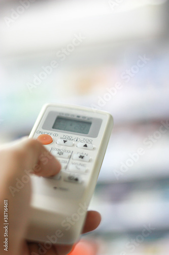 Copy space of and holding air conditioner remote control. Shallow depth of field. Vertical image.