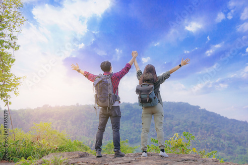 Couples hiker standing and open arms on mountain peak celebrate their freedom vacation.