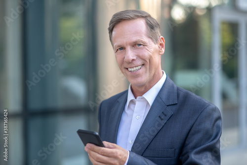 Smiling mature businessman checking his phone outside