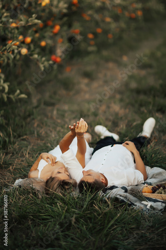 Young couple resting on the nature. Couple in love spend leisure time together at picnic. They lying on grass and holding hands.