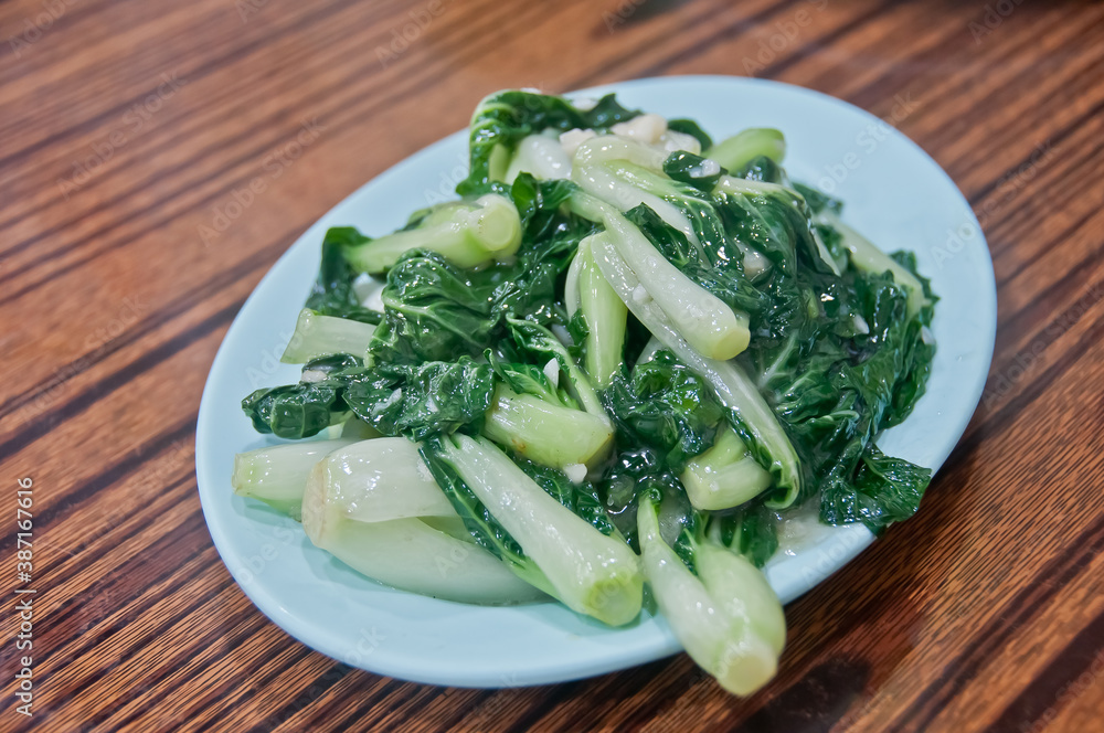 Fresh Chinese small cabbage choy sum stir fried vegatable with oyster sauce and garlic served hot on a plate Fresh Chinese small cabbage choy sum stir fried vegatable with oyster sauce and garlic served hot on a plate