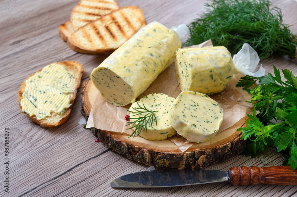 Healthy butter with dill, parsley in the form of a roll, slices for easy use. Herbal butter on a cutting board for toasted, sandwiches Healthy butter with dill, parsley in the form of a roll, slices for easy use. Herbal butter on a cutting board for toasted, sandwiches