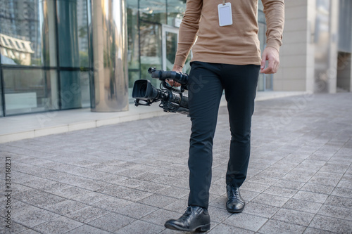 Close-up of male walking outside with camera in his right hand