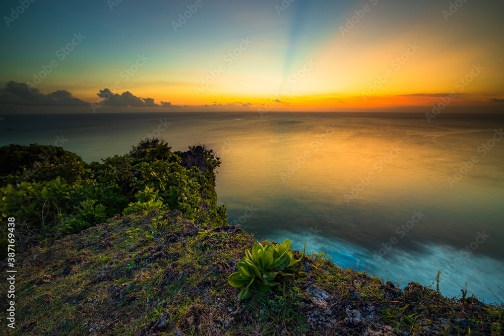 Seascape. Spectacular view from Uluwatu cliff in Bali. Sunset time. Blue hour. Ocean with motion foam waves. Colorful sky. Nature concept. Soft focus. Slow shutter speed.