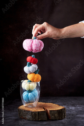 Five multi-colored knitted pumpkins in a glass and a woman's hand holding a pumpkin © watcherfox