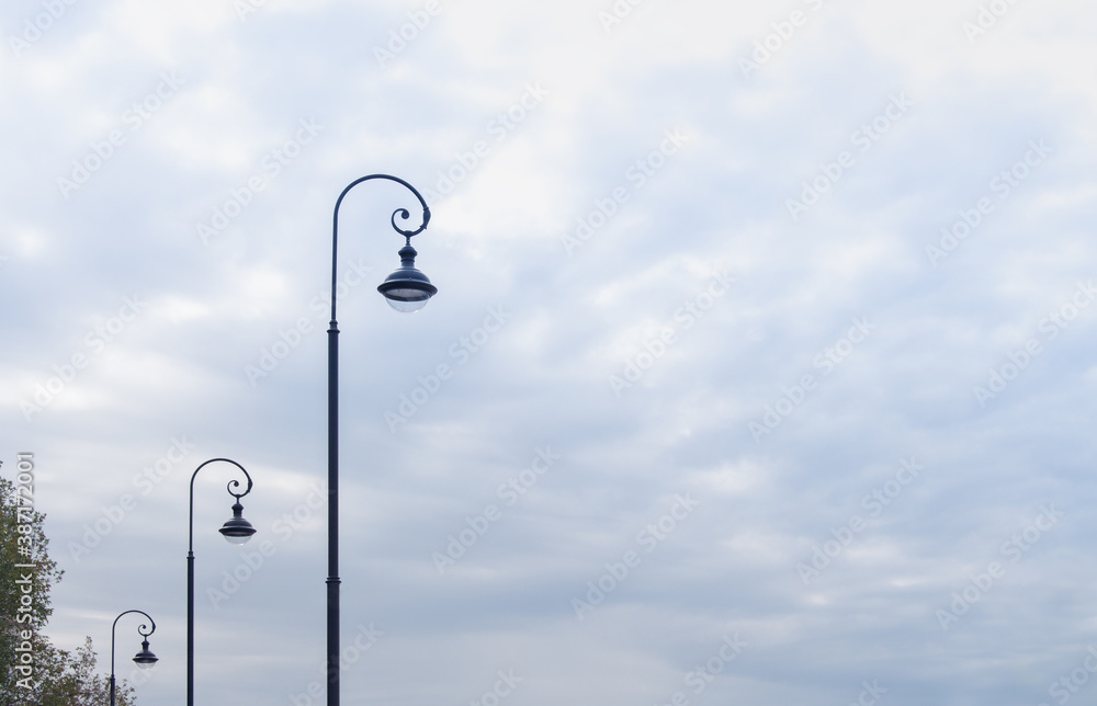 three street lamps against a cloudy sky three street lamps against a cloudy sky