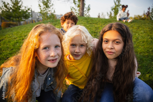 Unity. Interracial group of kids, girls and boys playing together at the park in summer day. Friendship has no race. Happiness, childhood, education, diversity concept. Look happy and sincere.