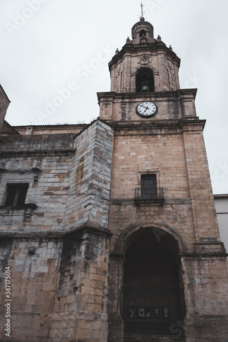 Medieval church with clock and bell in Portugalete, Spain. Religious architecture. Ancient cathedral tower with outdoor clock on facade. Elegant catholic church. Old stone church. with closed entrance