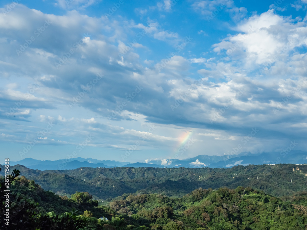 Naklejka premium Rural rainbow landscape, view of green meadows and mountains