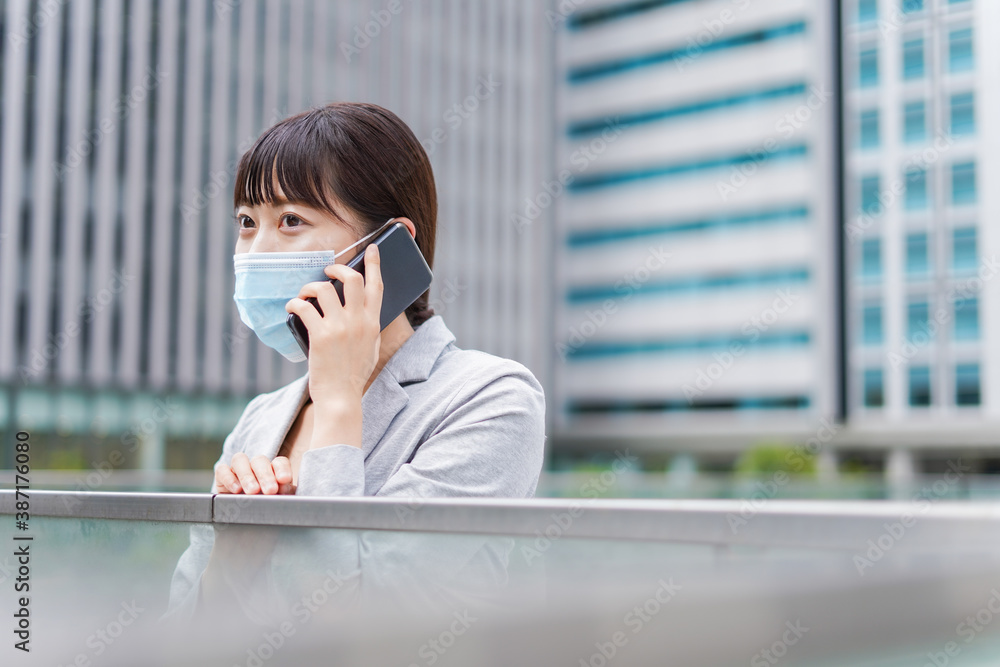 Fototapeta premium マスクをして電話をする若いビジネスウーマン