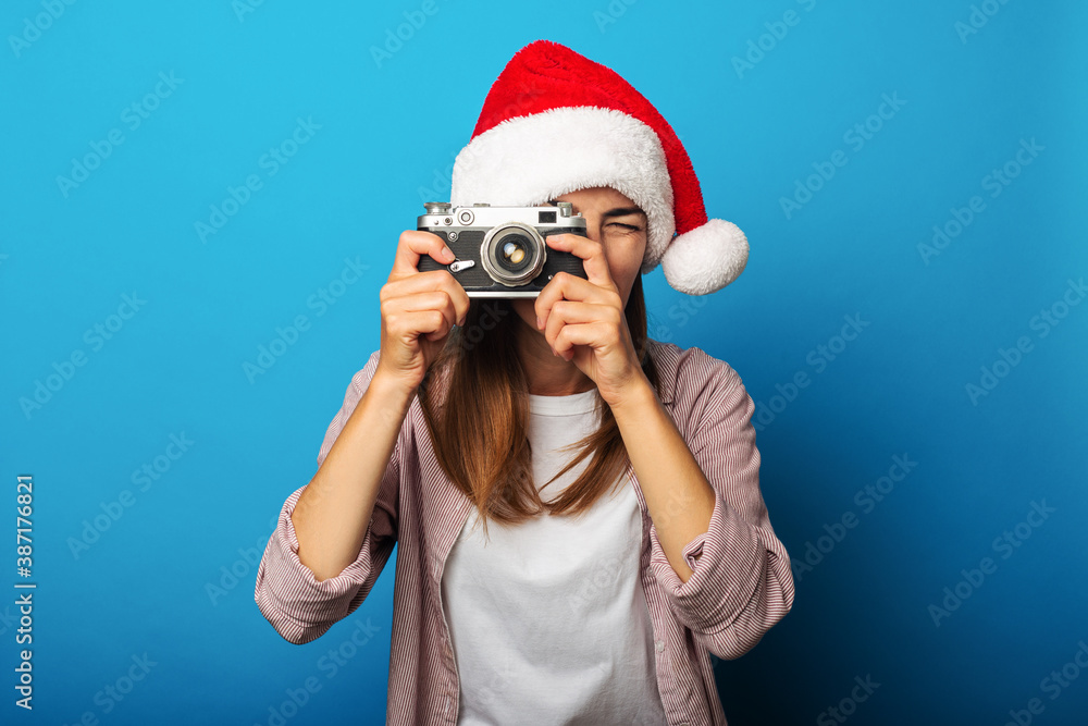Young woman in santa claus hat takes pictures with retro camera Young woman in santa claus hat takes pictures with retro camera