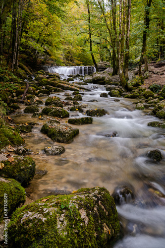 beautiful mountain stream with small waterfall in autumn forest landscape