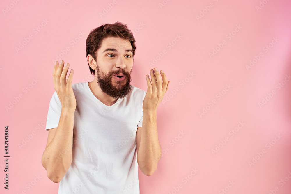 Man in white t-shirt gestures with hands emotions lifestyle cropped view pink background Man in white t-shirt gestures with hands emotions lifestyle cropped view pink background