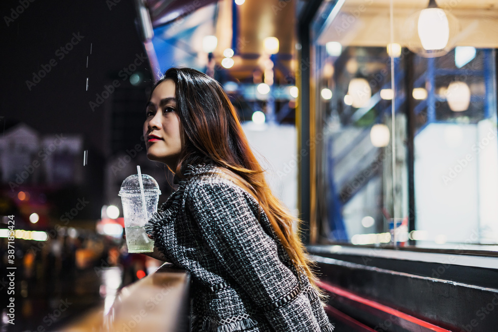 beautiful young lonely asian girl standing outside a cafe or restaurant, on a street night, it's raining, she is waiting for a bus or someone meets. beautiful young lonely asian girl standing outside a cafe or restaurant, on a street night, it's raining, she is waiting for a bus or someone meets.