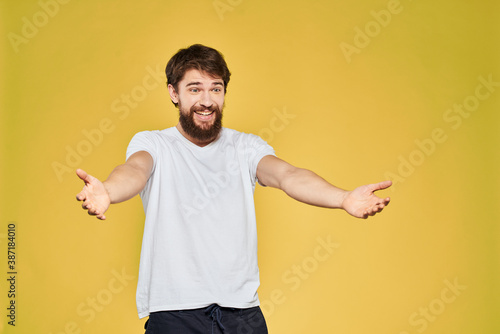 Man gesturing with hands emotions lifestyle white t-shirt yellow isolated background