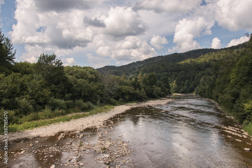 San river in the Bieszczady Mountains in Poland. Clear water and interesting rock formations at the bottom of the river. Shores surrounded by green vegetation